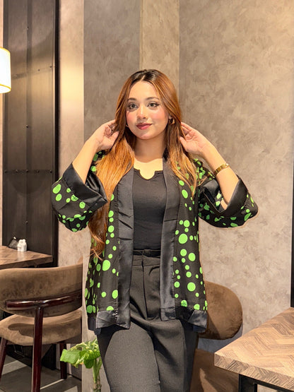 Woman posing in a modern cafe setting with tables and chairs wearing Black Green Polka Dot Kimono.