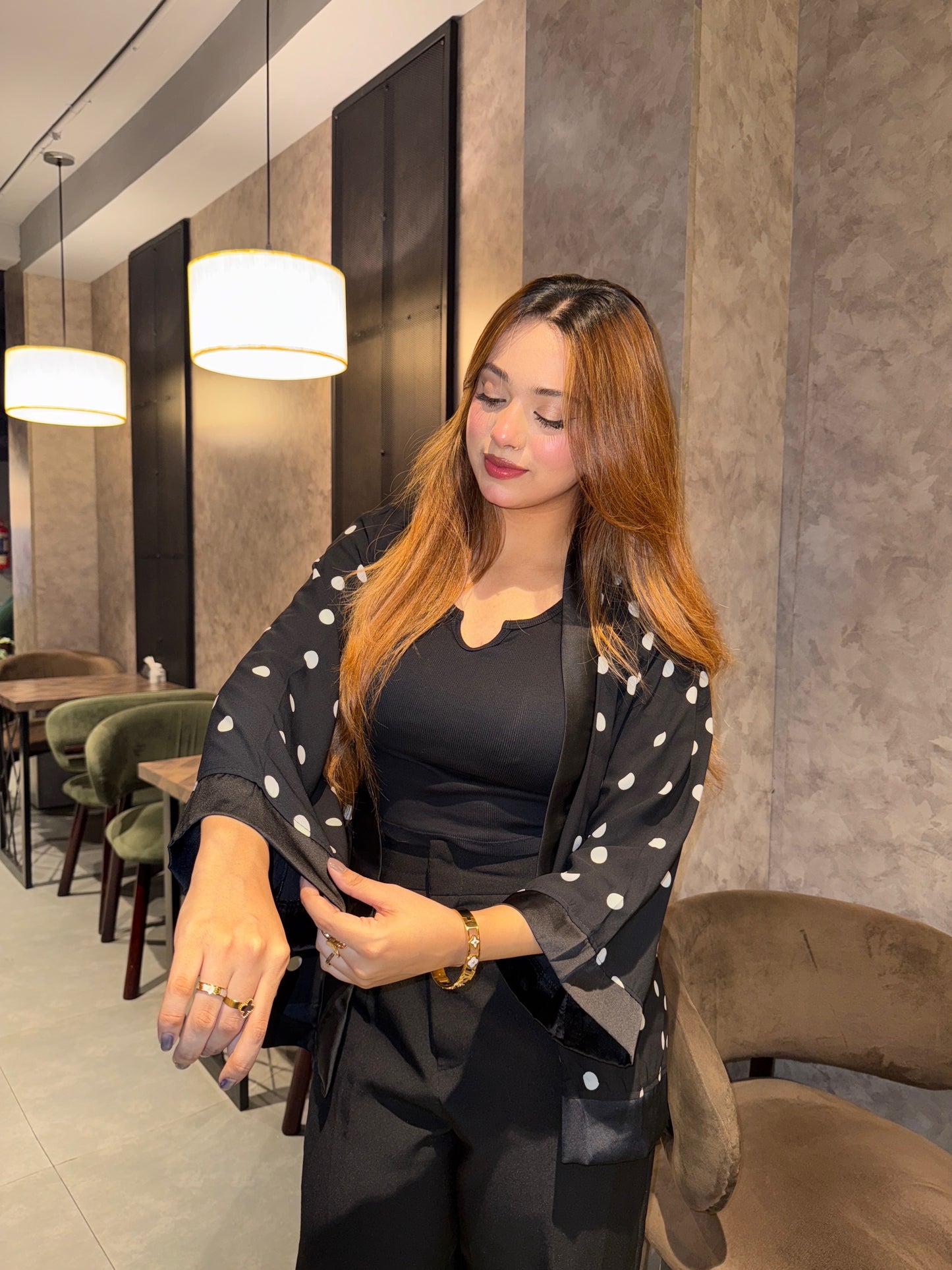 Woman in a black Polka dot Kimono and black outfit standing in a modern interior setting.