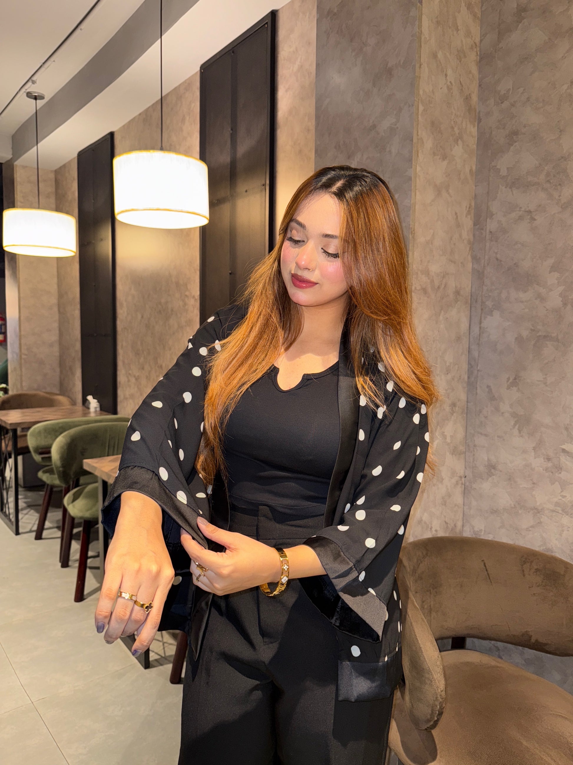 Woman in a black Polka dot Kimono and black outfit standing in a modern interior setting.