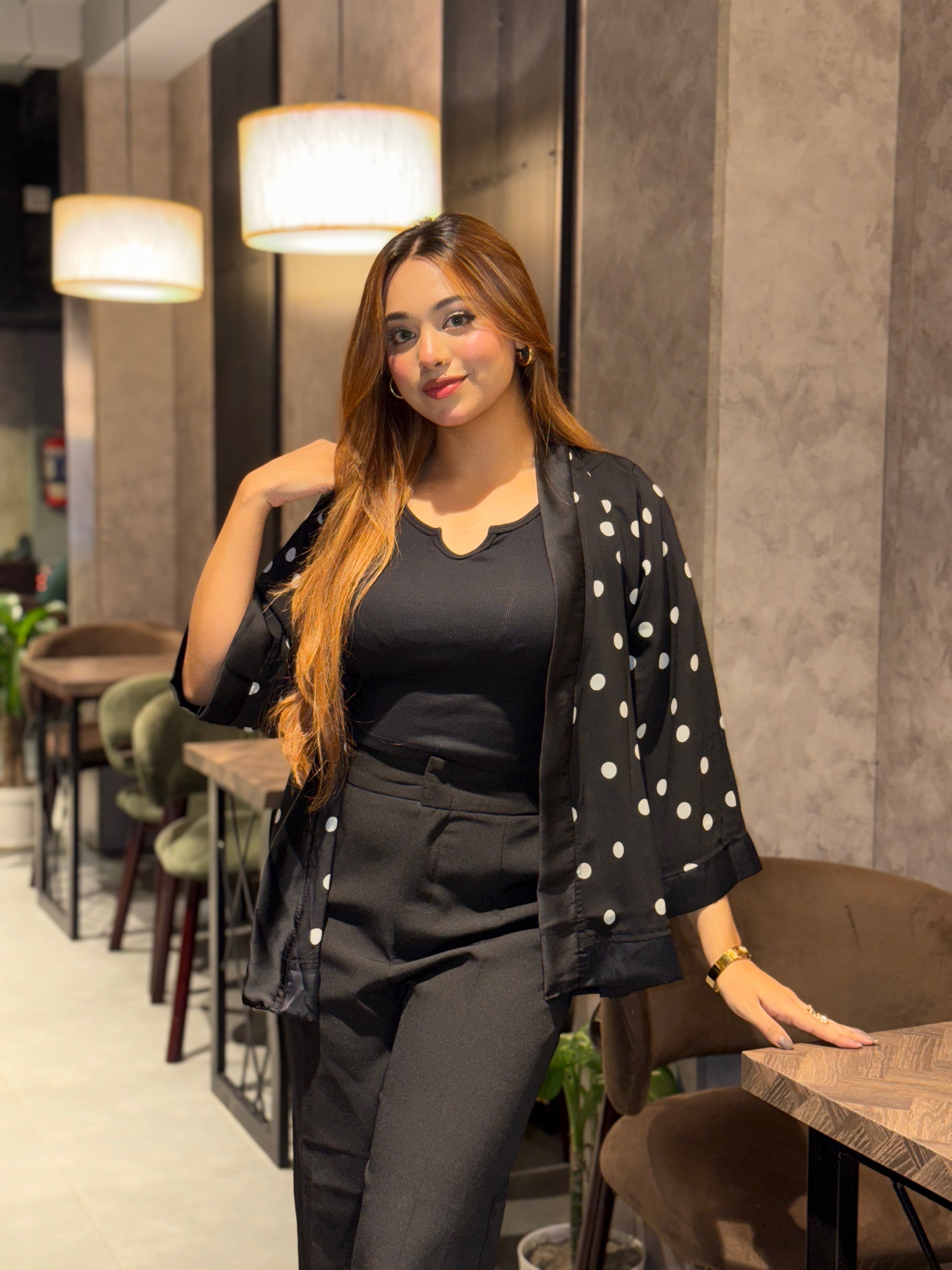 Woman in a polka dot Kimono and black outfit sitting in a modern cafe.