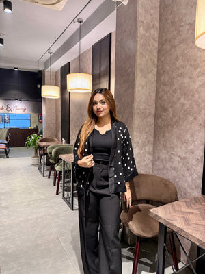 Woman standing in a modern cafe interior with tables and chairs wearing black Polka dot Kimono Outfit