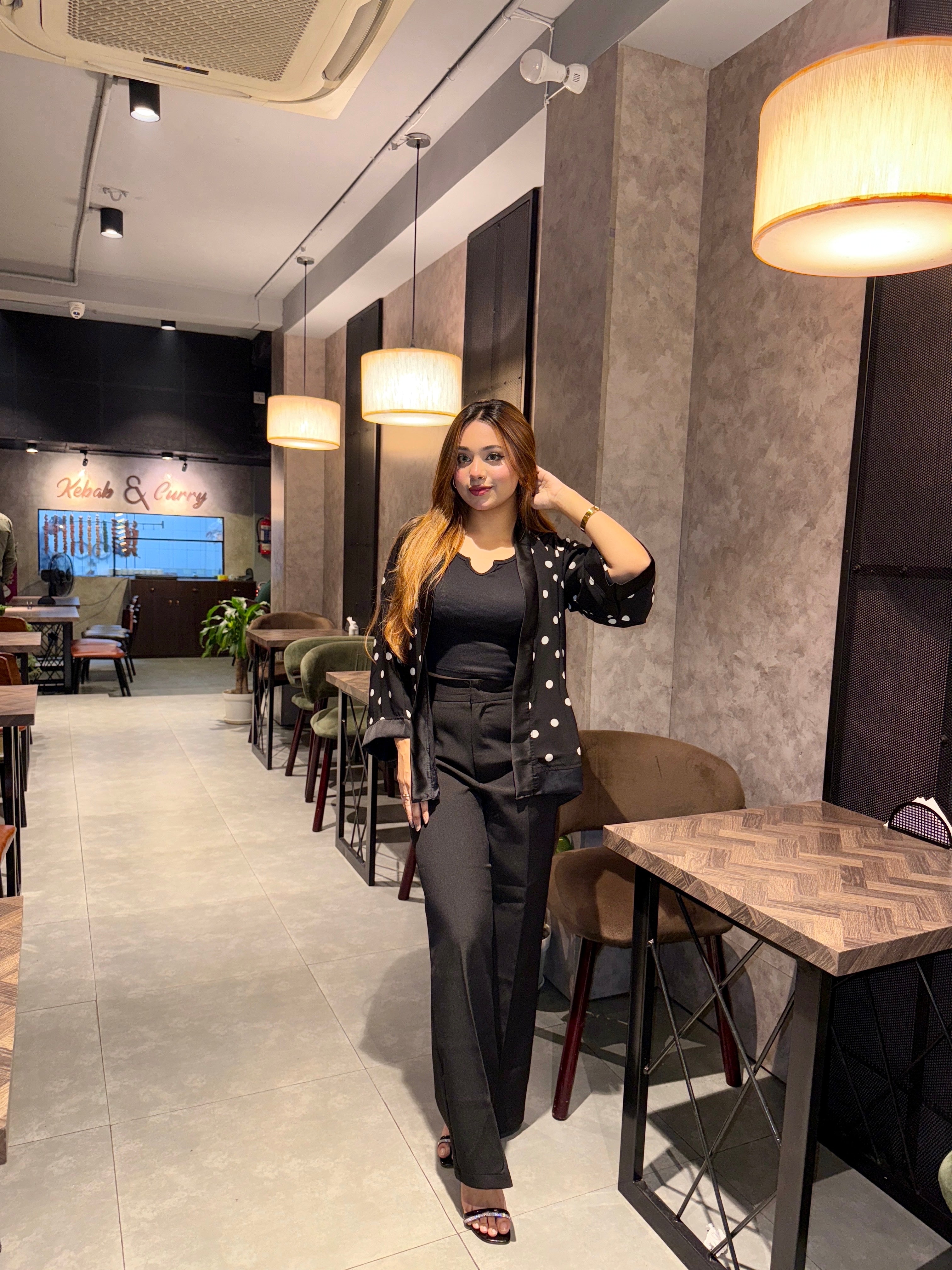 Woman in a black white Polka dot Kimono Outfit outfit standing in a modern restaurant interior.