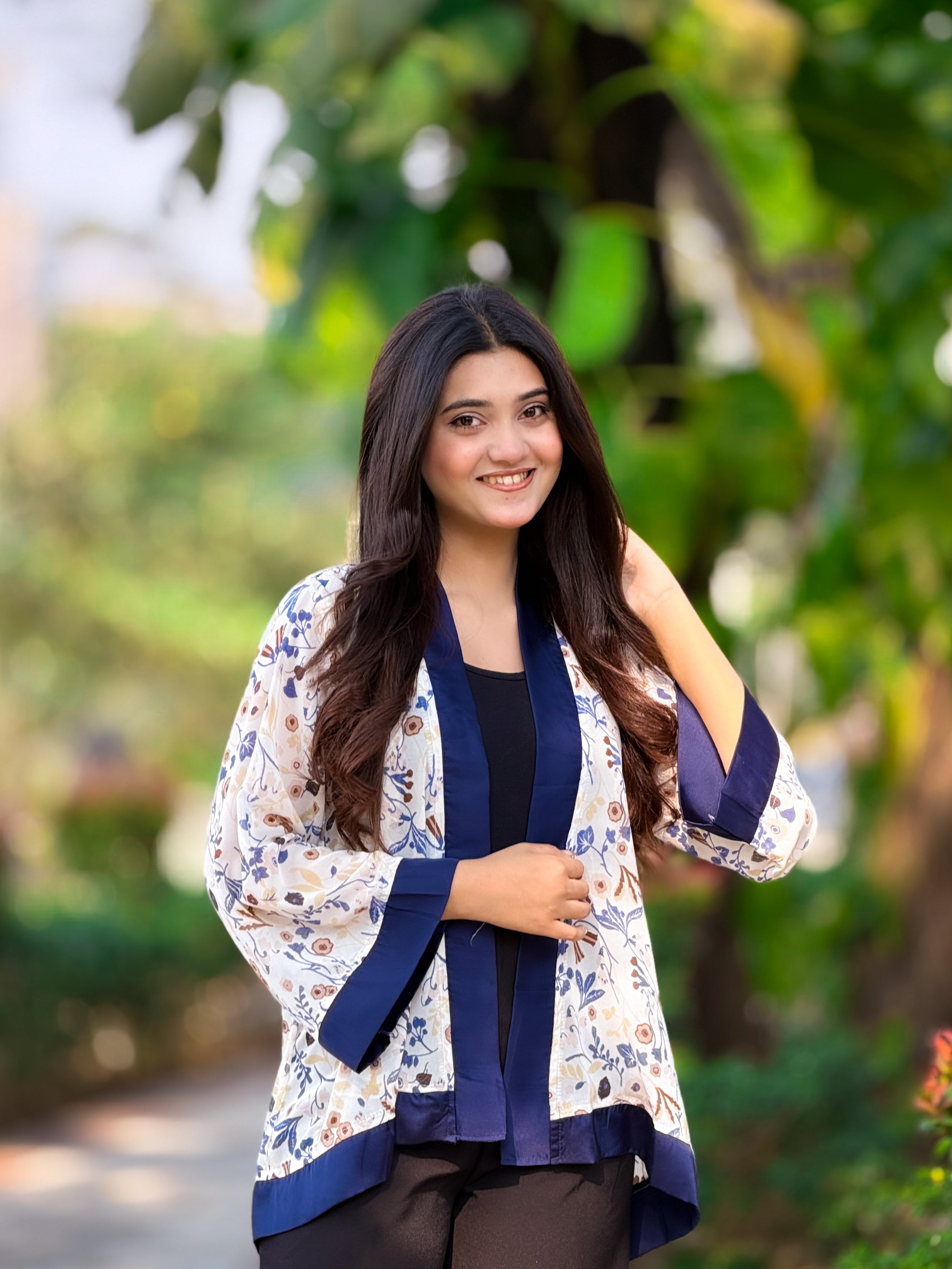 Woman wearing a floral kimono-style jacket with a blurred green background