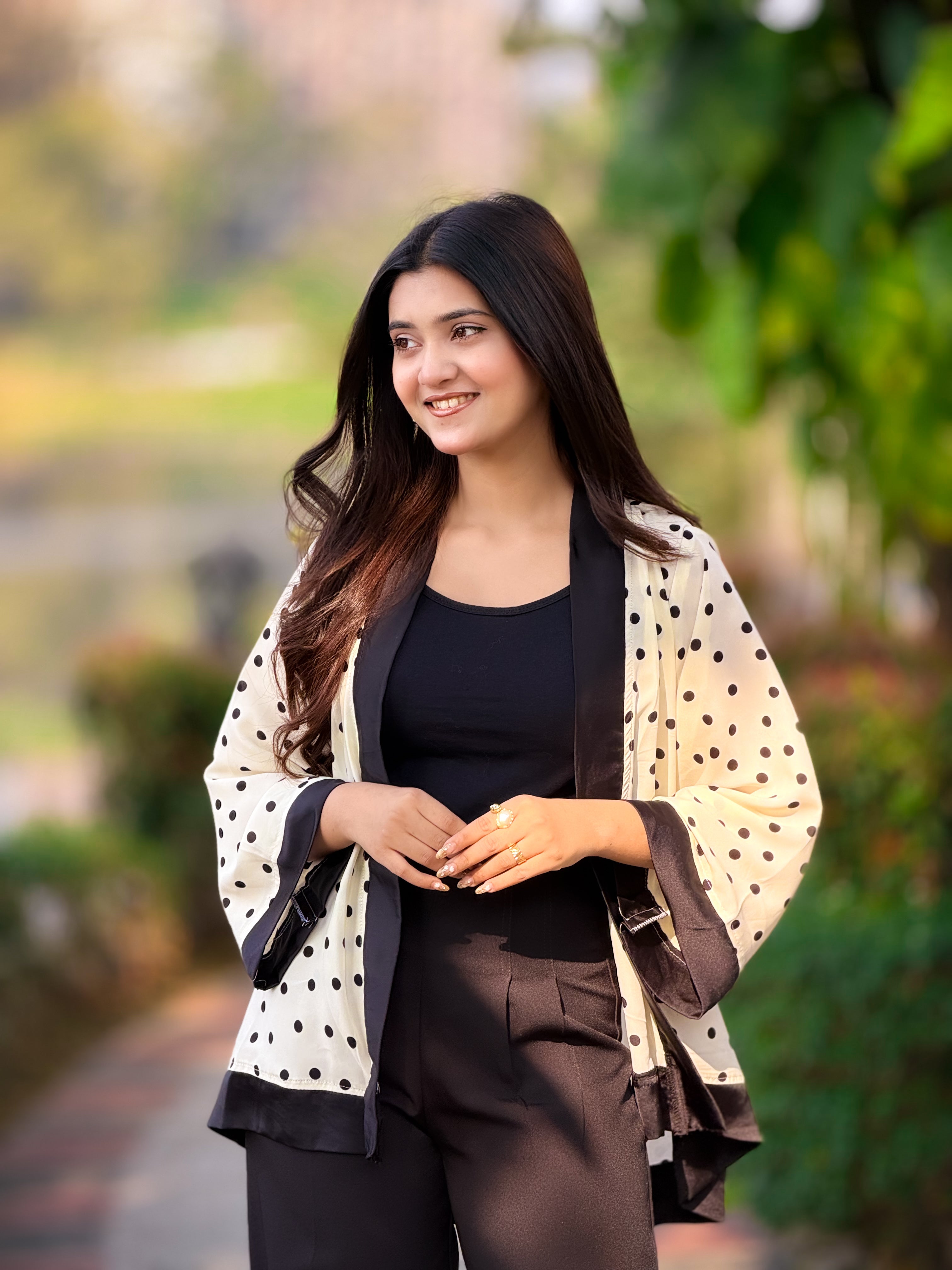 Woman wearing a black blazer and polka dot cardigan outdoors