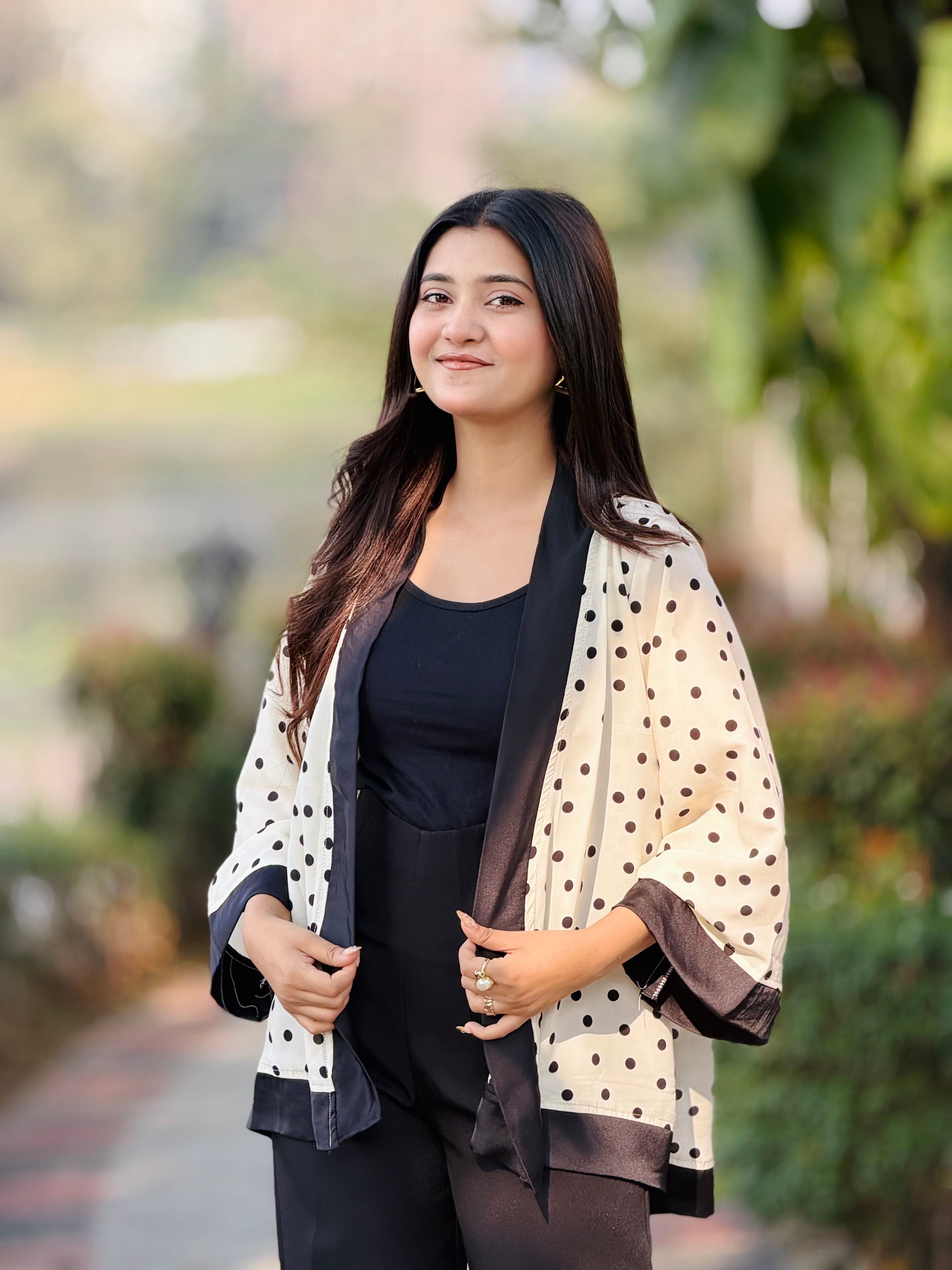Woman wearing a polka dot scarf outdoors with greenery in the background