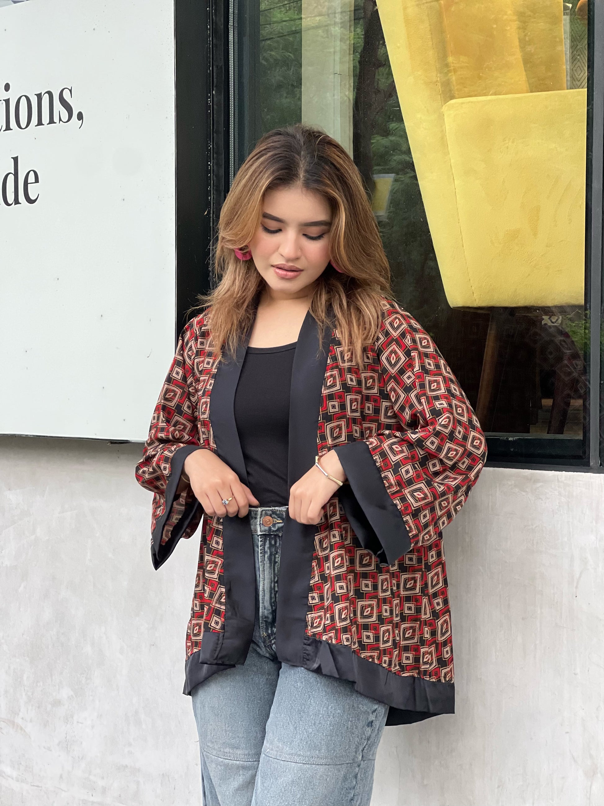 Woman wearing a patterned short kimonos in front of a store window