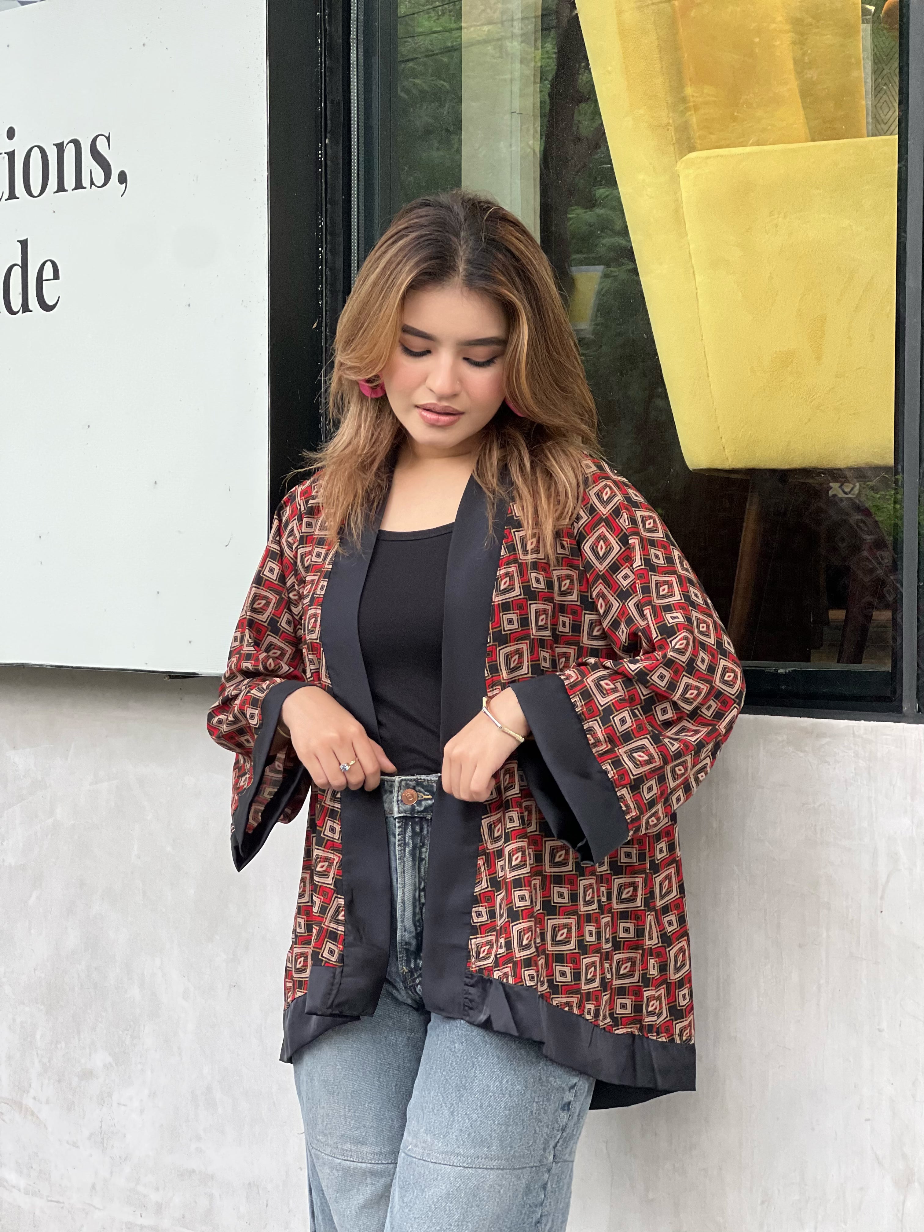 Woman wearing a patterned short kimonos in front of a store window