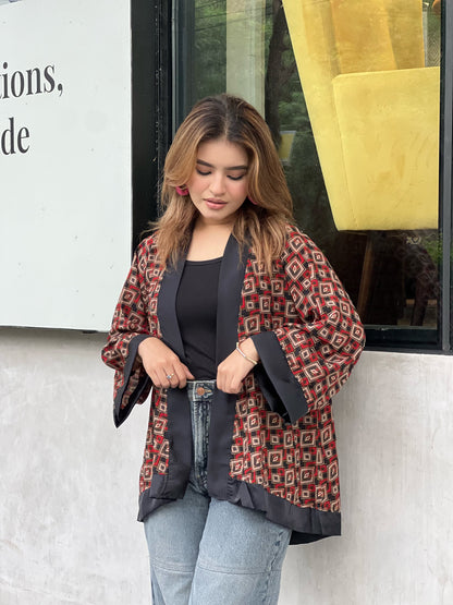 Woman wearing a patterned short kimonos in front of a store window