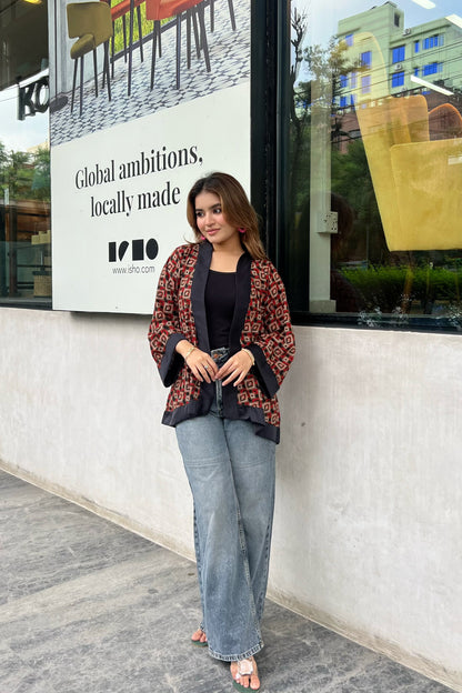 Woman wearing short kimonos standing in front of a store window with an advertisement in the background