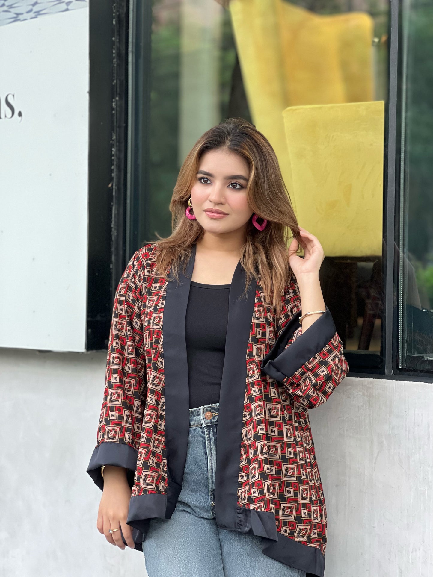 Woman wearing a patterned short kimonos in front of a store window