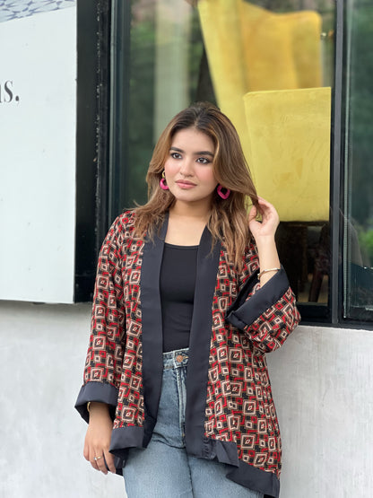 Woman wearing a patterned short kimonos in front of a store window