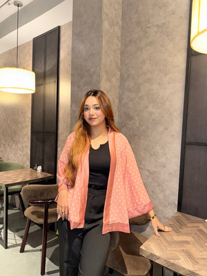 Woman sitting in a modern interior setting with a neutral color scheme by wearing our Misty polka dot Kimono over a black top