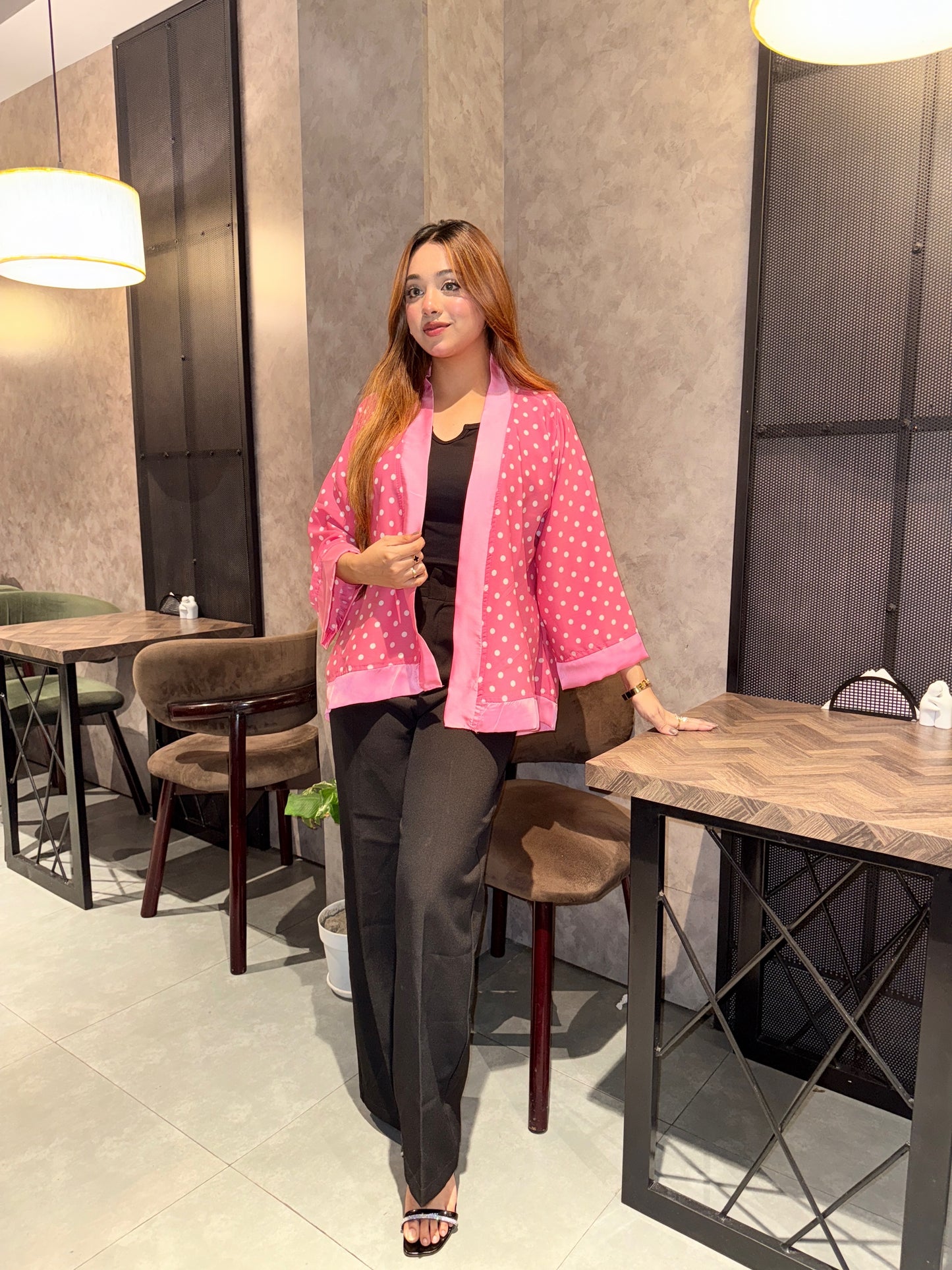 Woman in a pink polka dot kimono sitting at a table in a modern cafe.
