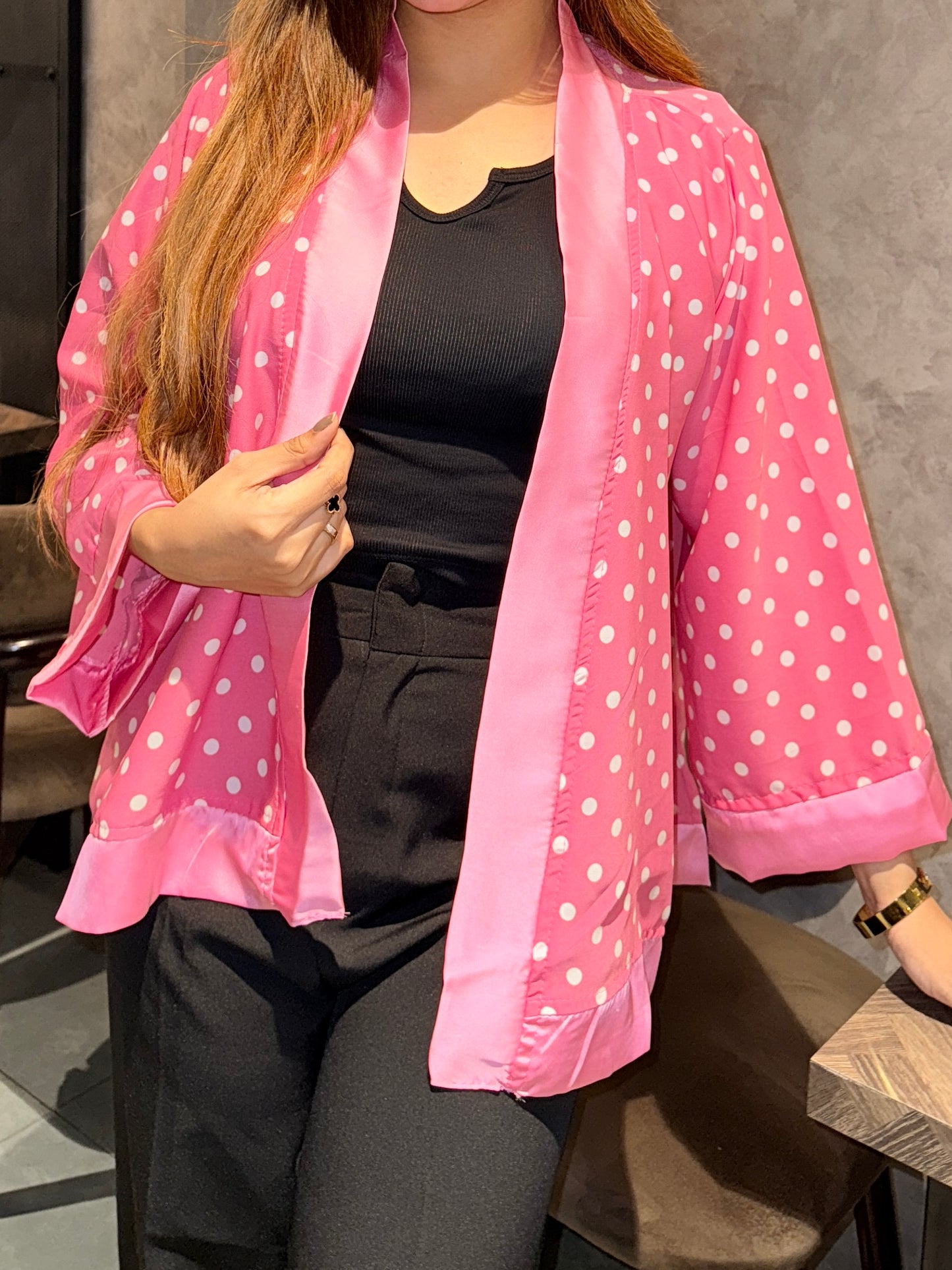 Person wearing a pink polka dot kimono over a black outfit.