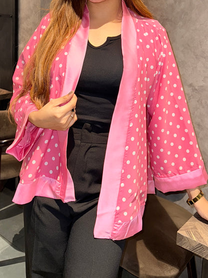 Person wearing a pink polka dot kimono over a black outfit.