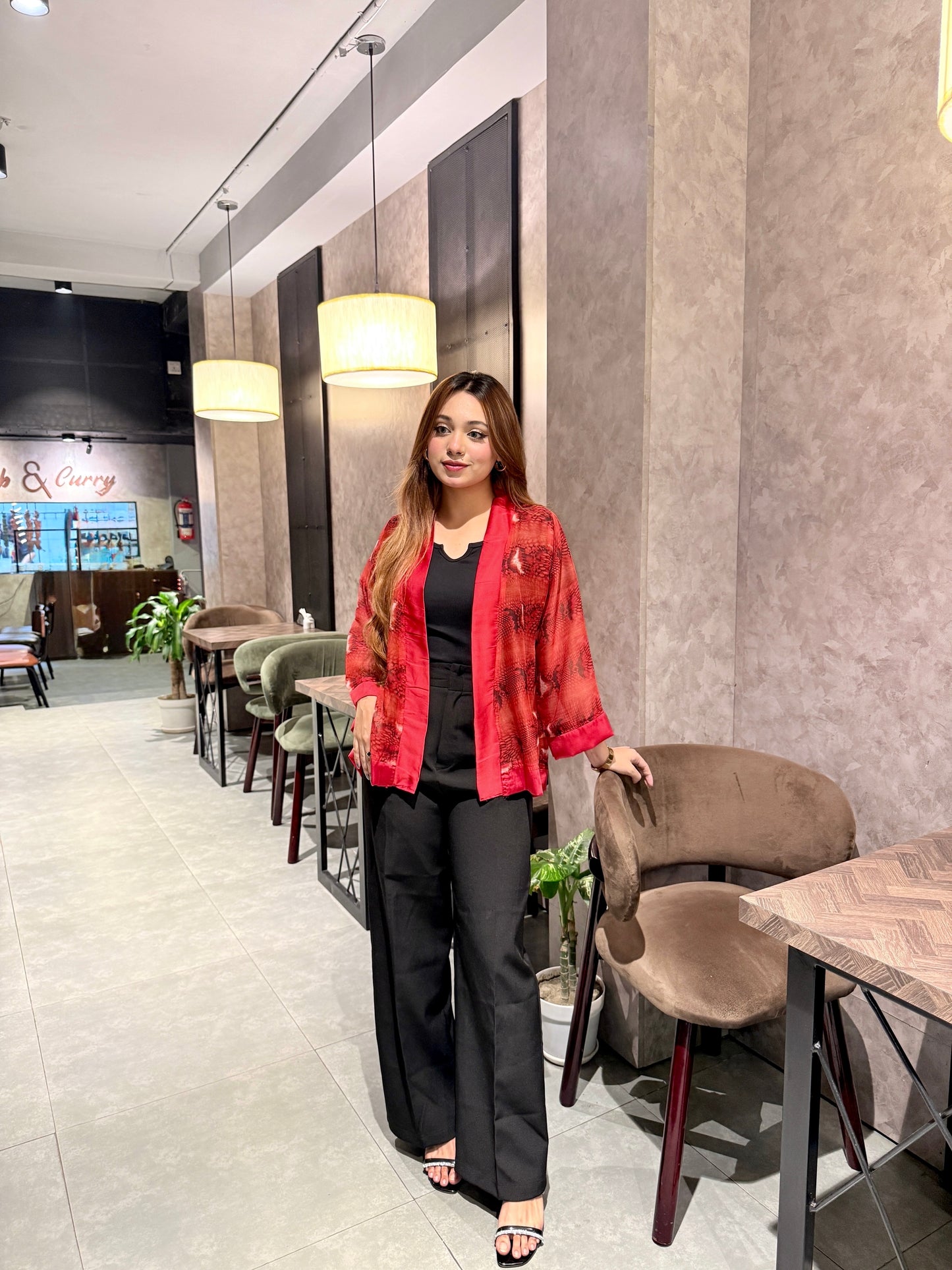 Woman in a red snake print kimono standing in a modern cafe interior.