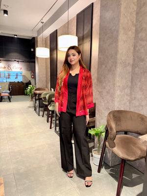 Woman in a red snake print kimono and black pants standing in a modern interior setting.