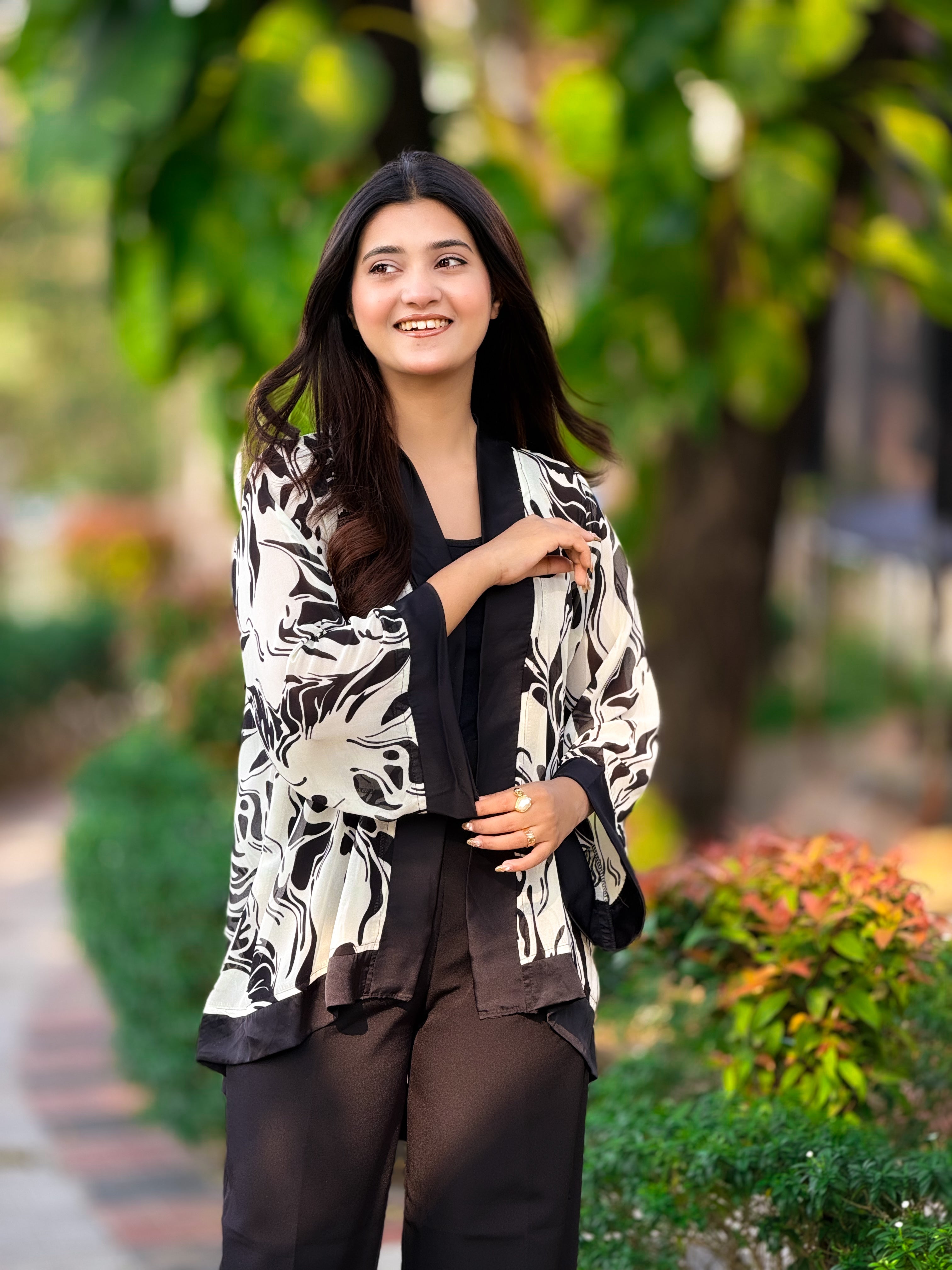 Woman wearing a black and white patterned jacket in a garden setting