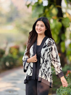 Woman wearing a patterned jacket outdoors with greenery in the background