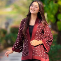 Woman wearing a polka dot jacket outdoors with greenery in the background
