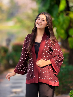 Woman wearing a polka dot jacket outdoors with greenery in the background