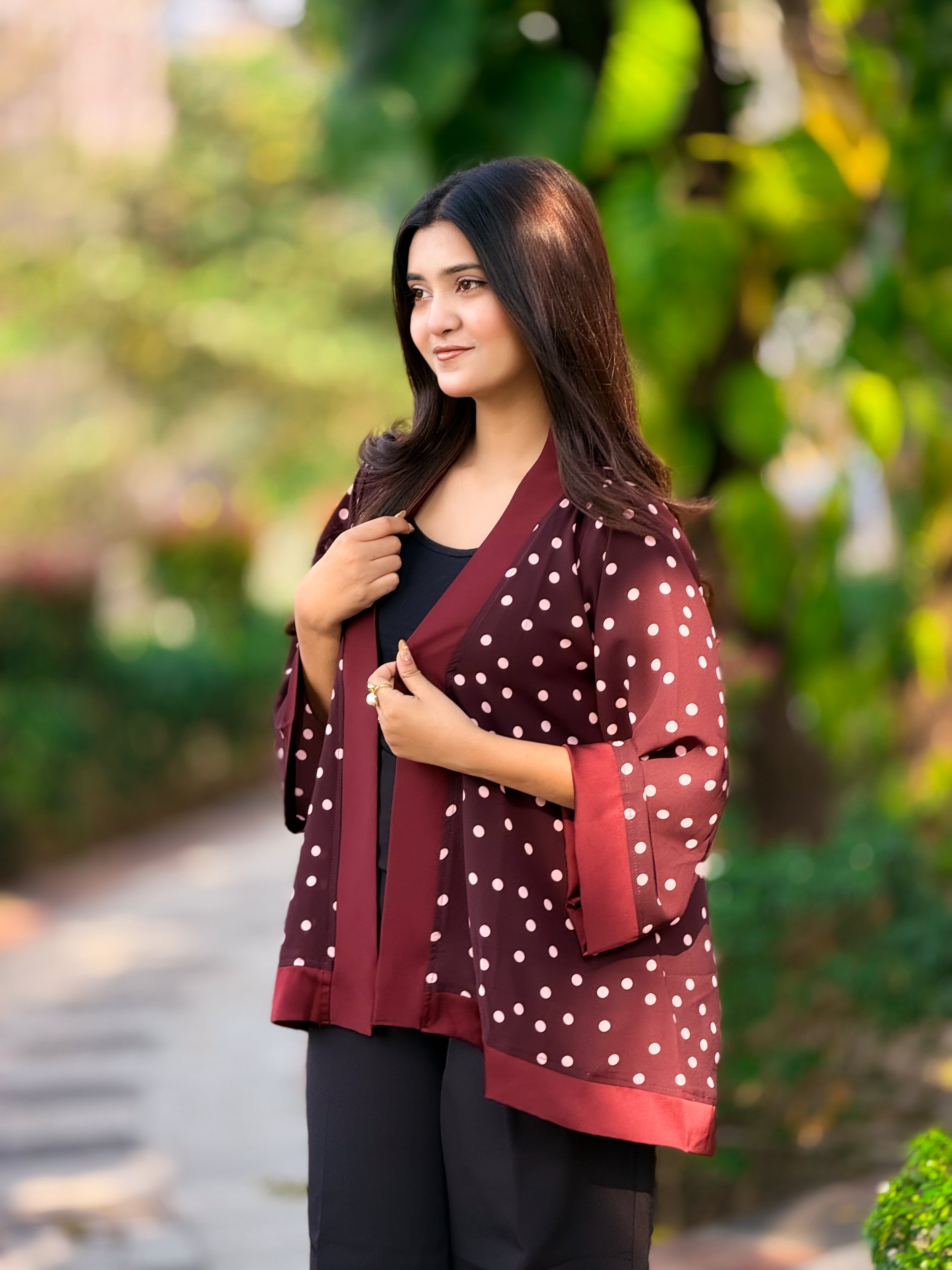Woman wearing a maroon cardigan with white polka dots outdoors