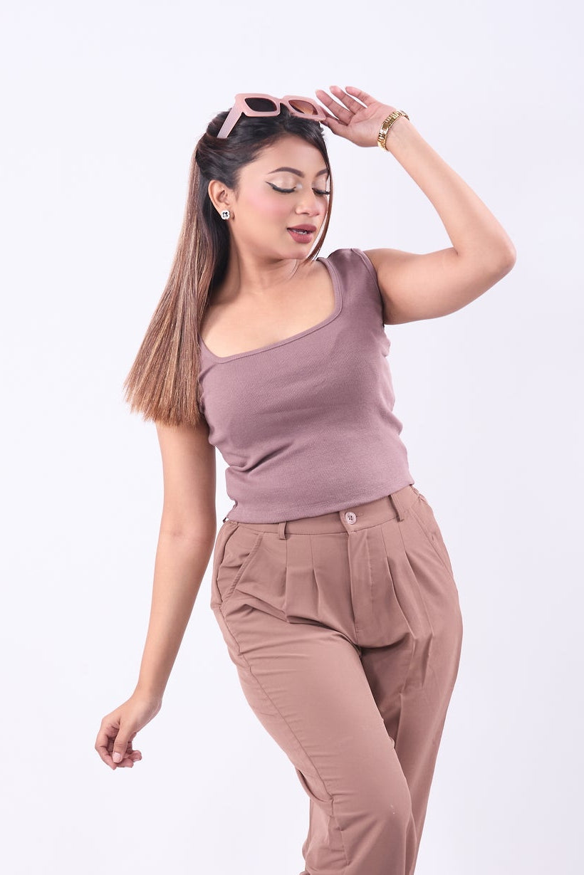 Woman wearing a mauve sleeveless top and beige pants on a white background