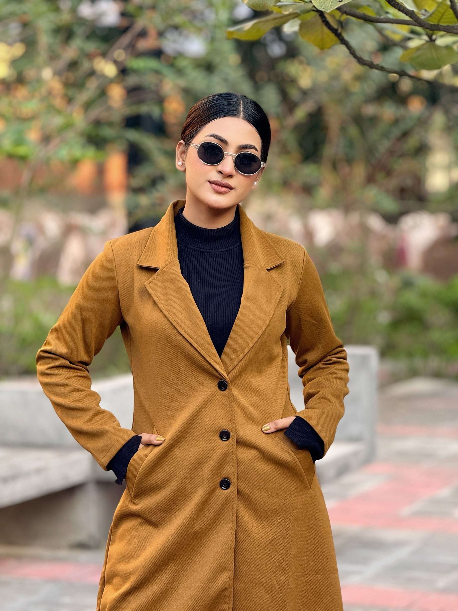 Woman wearing a brown coat and sunglasses outdoors