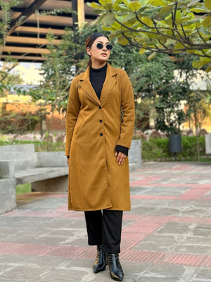 Person wearing a mustard yellow coat in an outdoor setting with trees and benches.