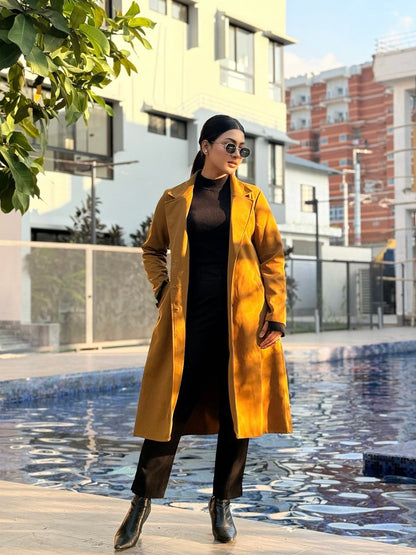 Woman in a yellow coat standing by a pool with buildings in the background