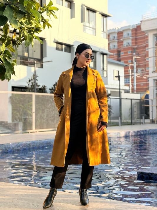 Woman in a yellow coat standing by a pool with buildings in the background