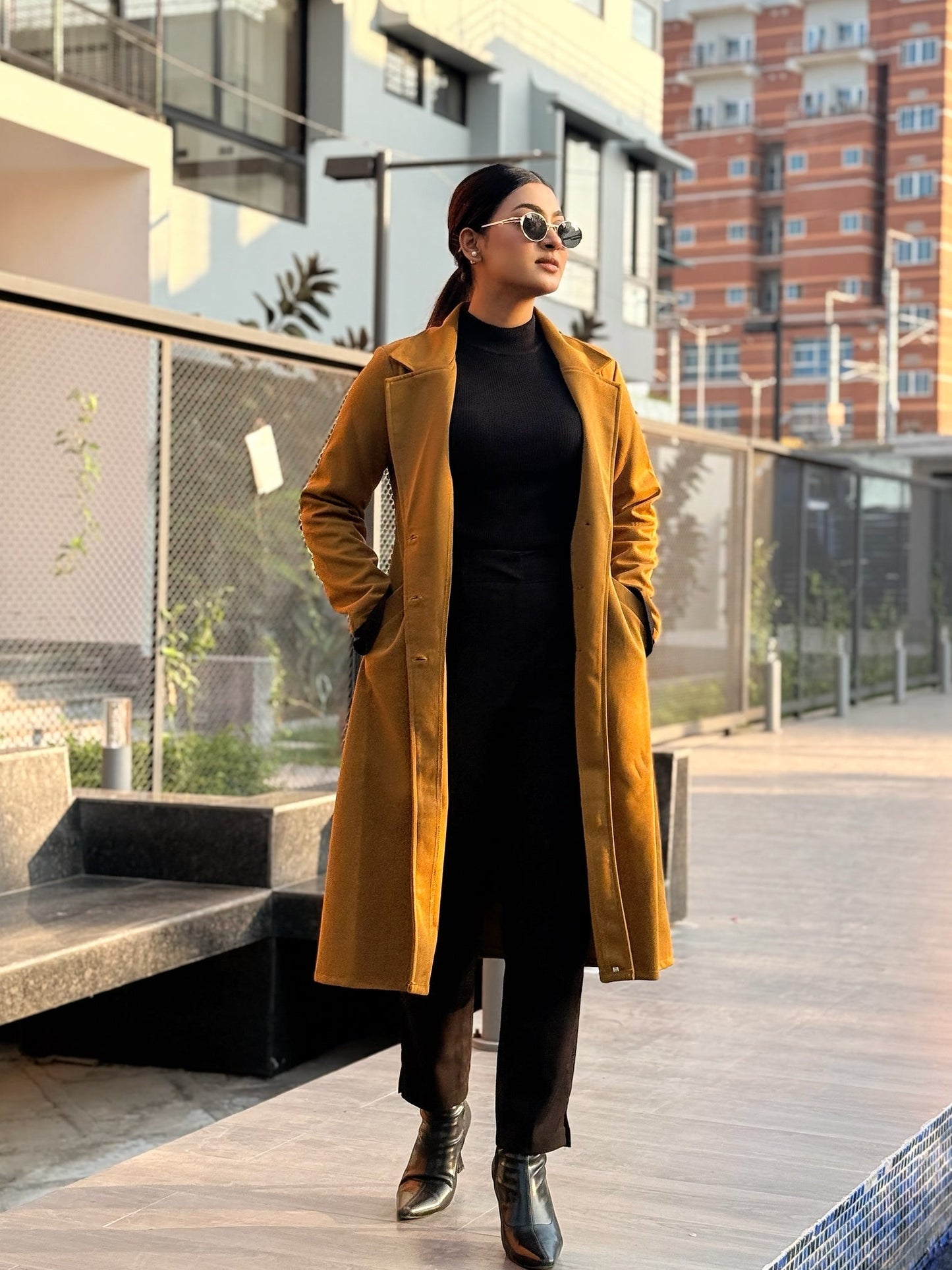 Person wearing a yellow coat and black outfit in an urban setting