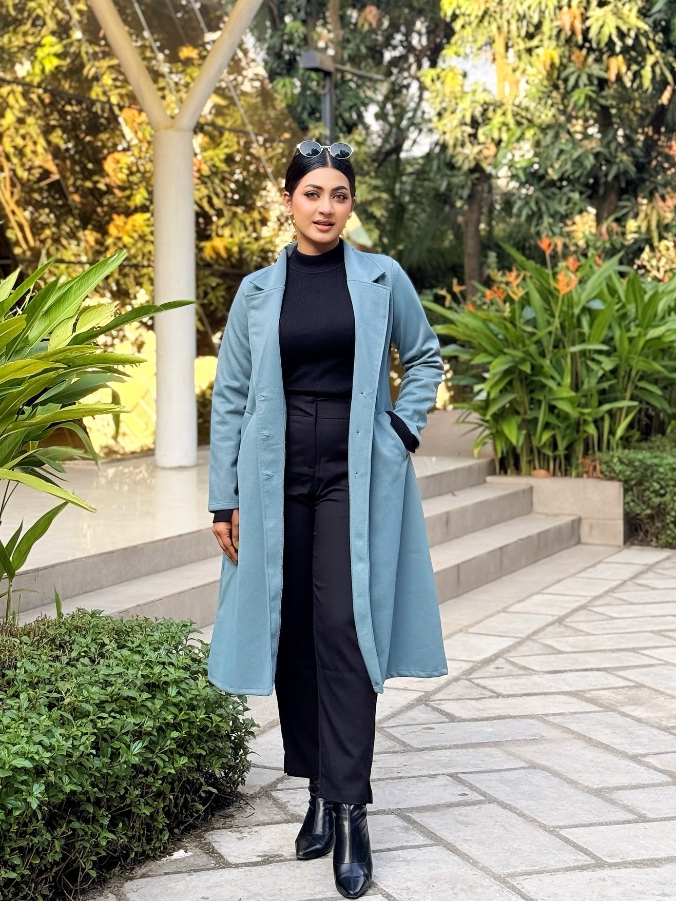 Person wearing a long blue coat standing in a garden setting