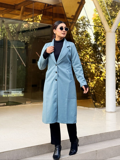 Woman in a light blue coat walking outdoors near modern architecture