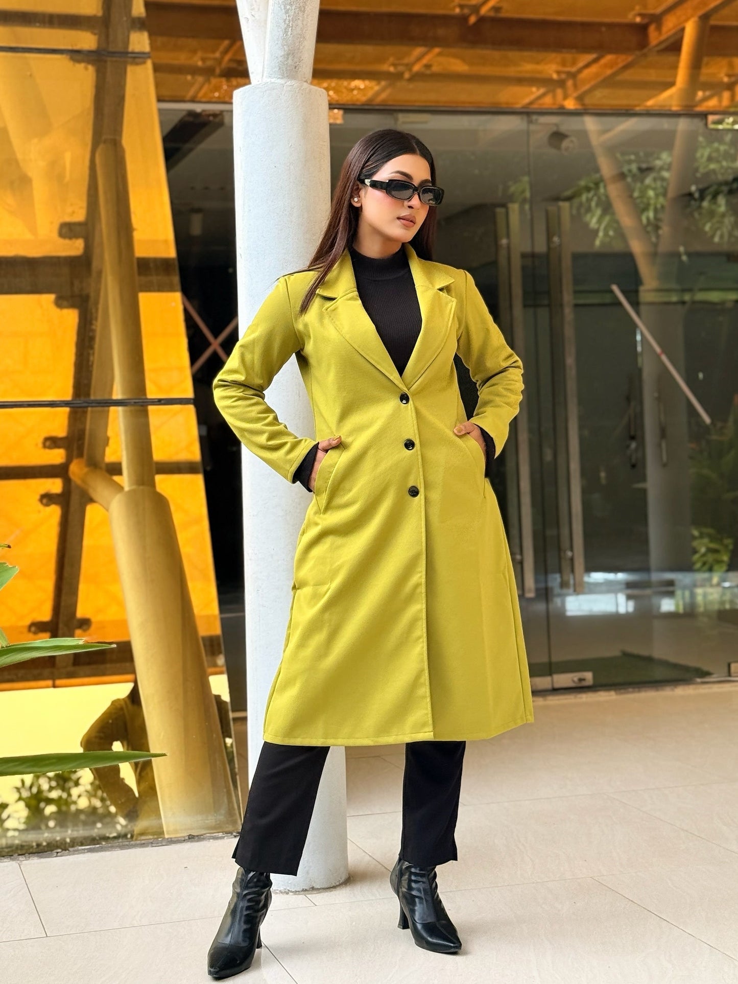 Person wearing a bright yellow coat in an indoor setting with modern architecture.