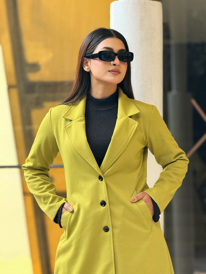 Woman wearing a yellow coat and sunglasses in an urban setting