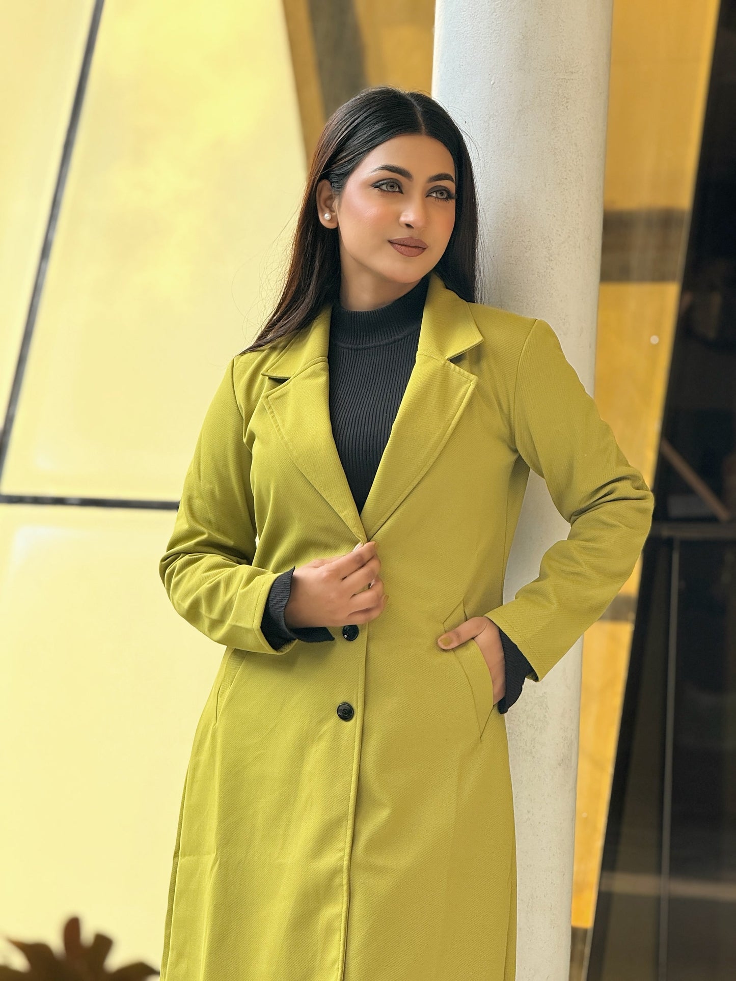Woman wearing a green trench coat against a yellow and black background