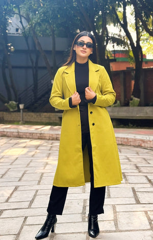 Person wearing a yellow coat and sunglasses outdoors on a paved path with trees in the background