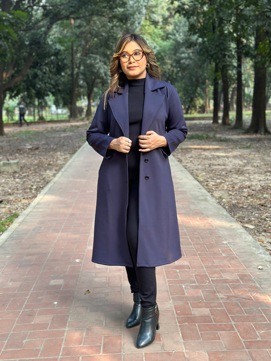 Woman wearing a long dark coat in a park setting