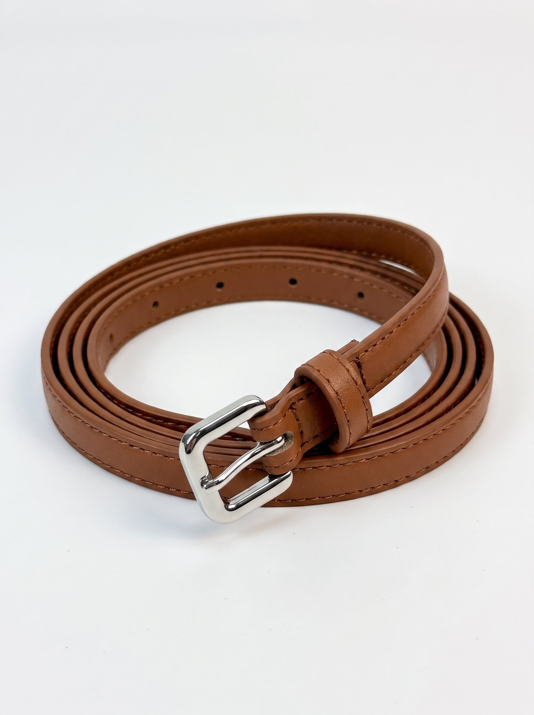 A brown faux leather belt with a silver-tone metal buckle, neatly coiled on a white background.