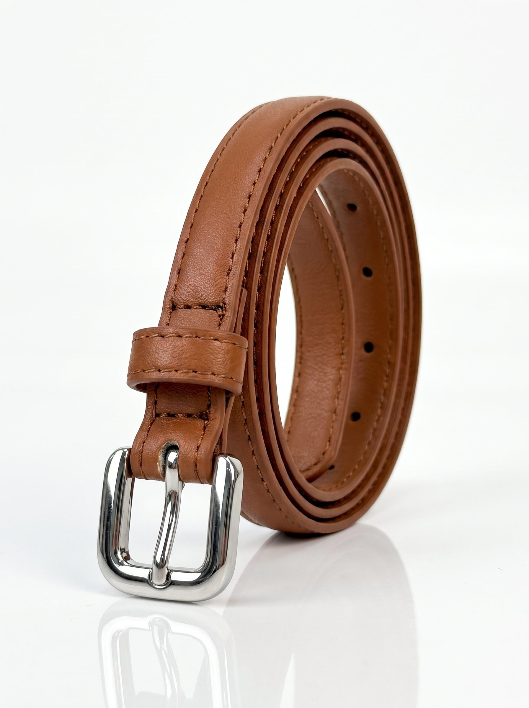 A brown leather belt with a polished silver-tone metal buckle, neatly coiled on a reflective white surface.