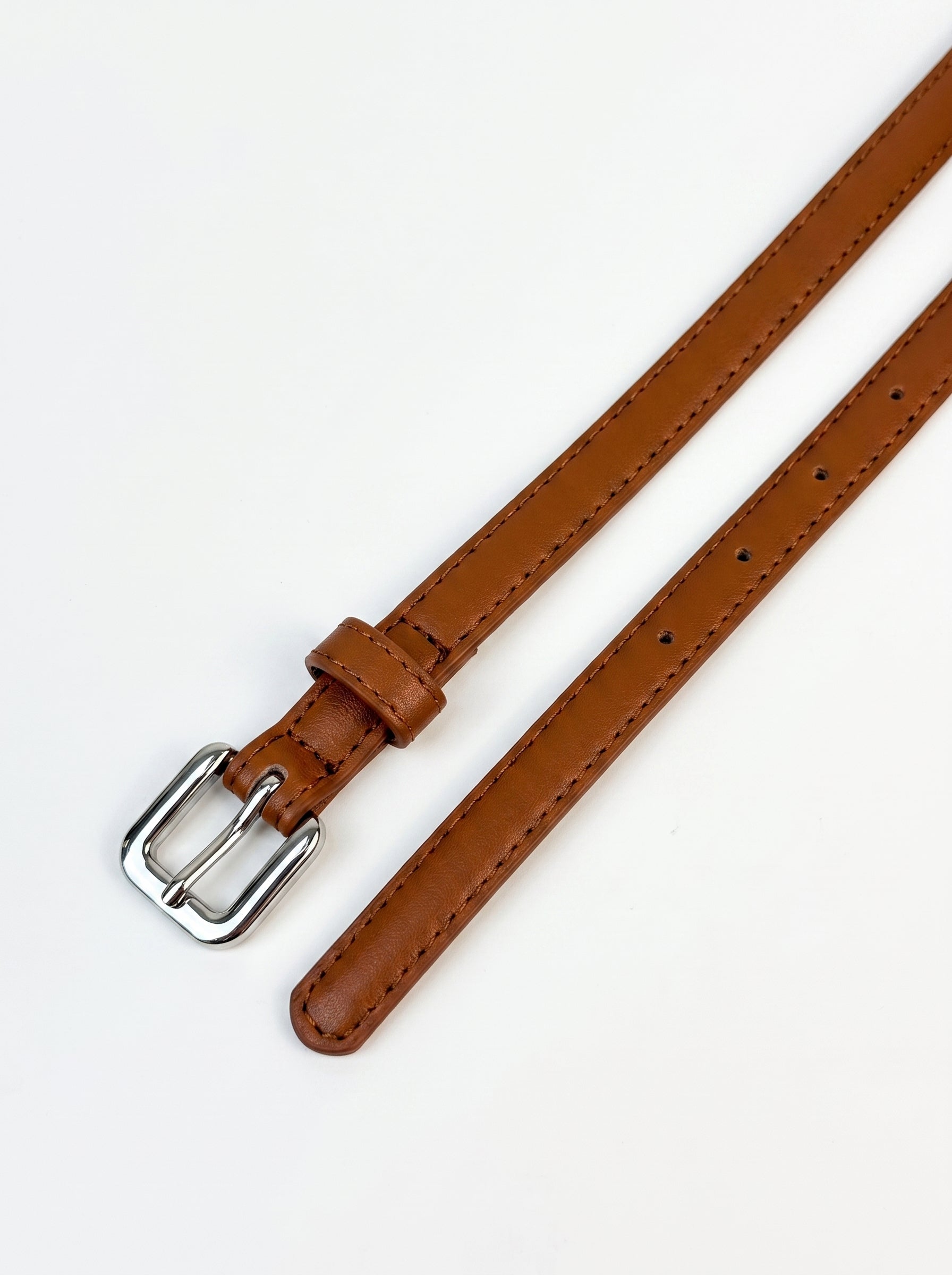 A brown leather watch strap with a silver-tone metal buckle, laid diagonally on a clean white background.