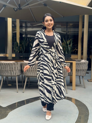 Woman wearing a zebra print long shrug in an indoor setting with tables and chairs.
