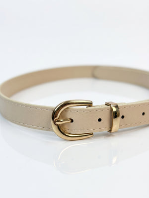 A beige faux leather belt with a polished gold-tone metal buckle, shown coiled on a reflective white surface.