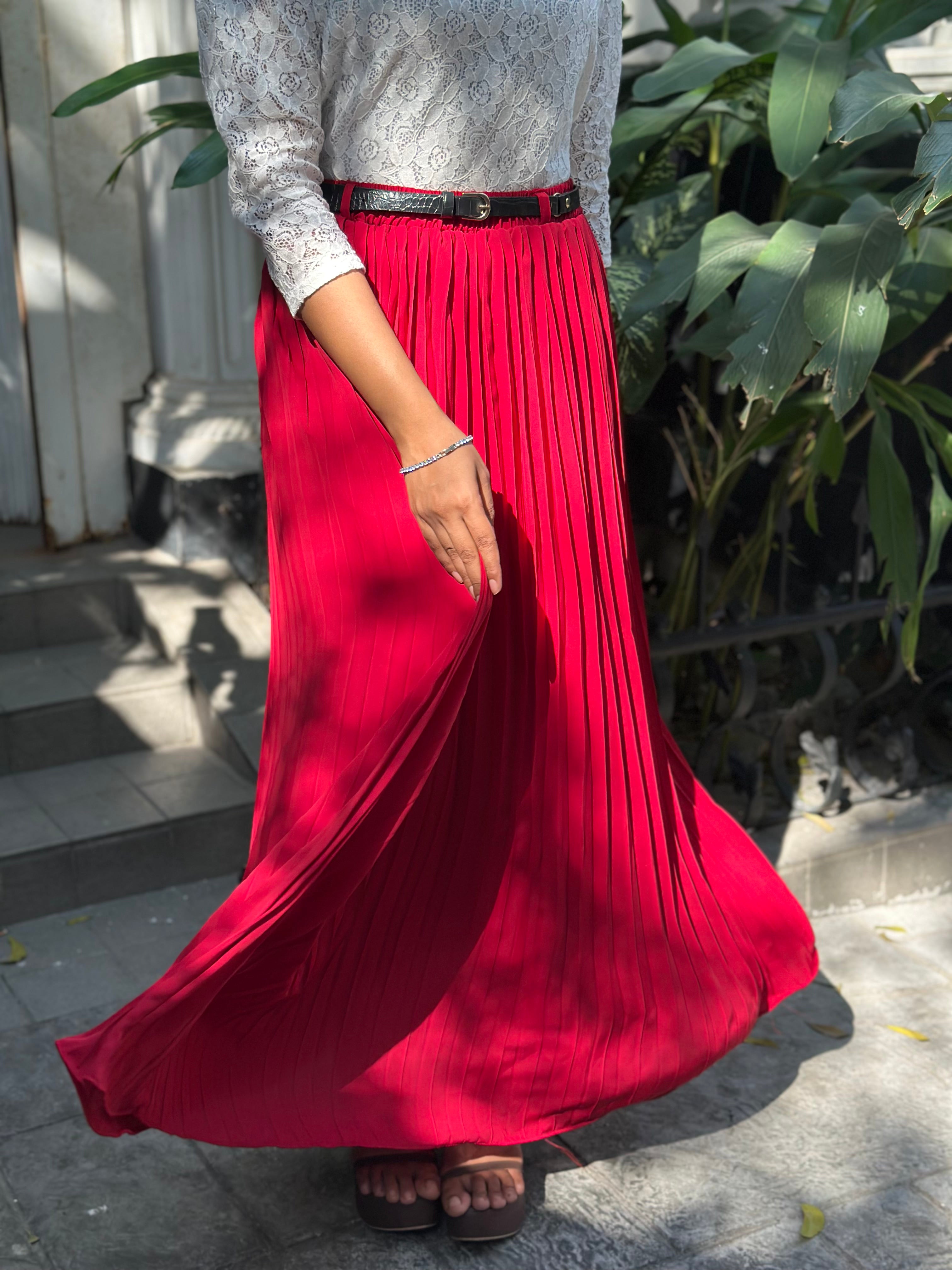 Person wearing a long red pleated skirt with a blurred background