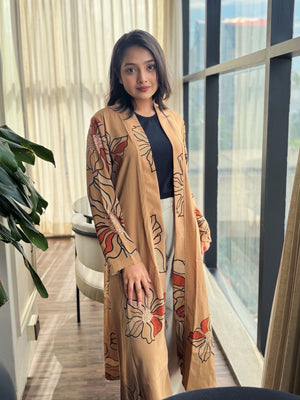 Woman wearing a beige floral-patterned Shrug in an indoor setting with large windows.