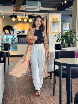 Woman in a stylish outfit with a long floral Shrug in a modern cafe setting
