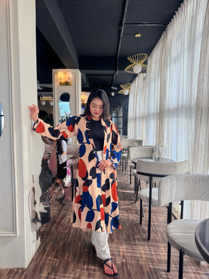 Woman in a colorful patterned long shrug standing in a modern restaurant.