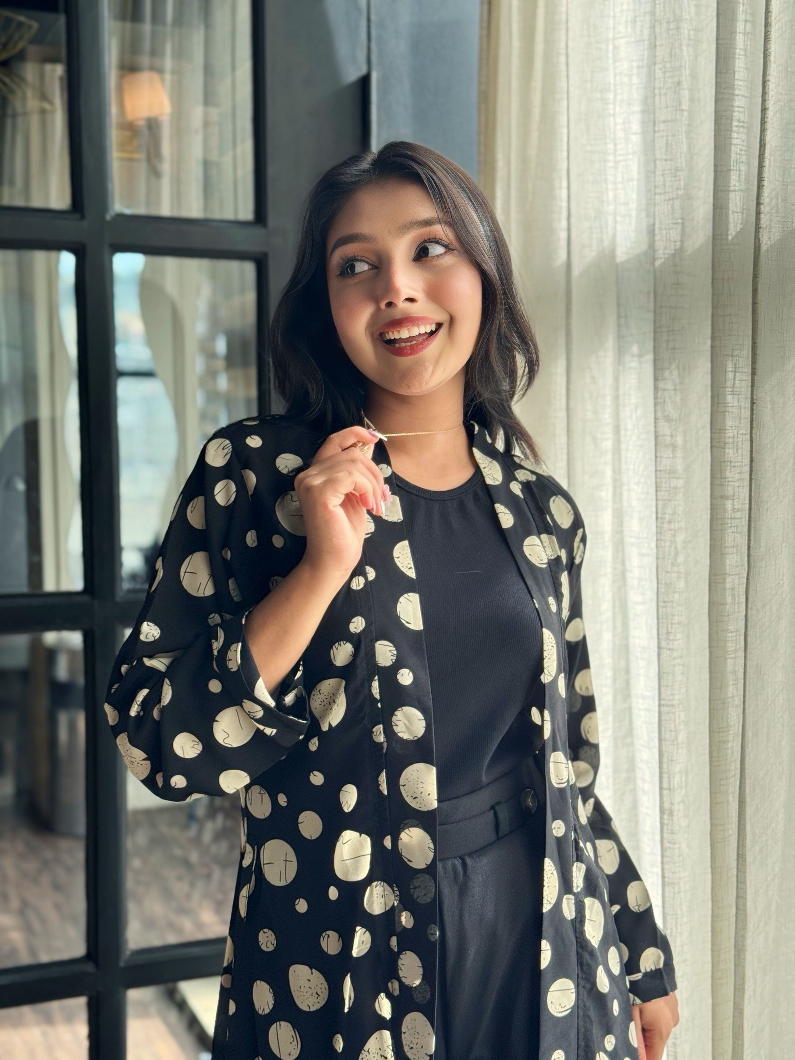 Woman wearing a black dress with white polka dot pattern indoors.
