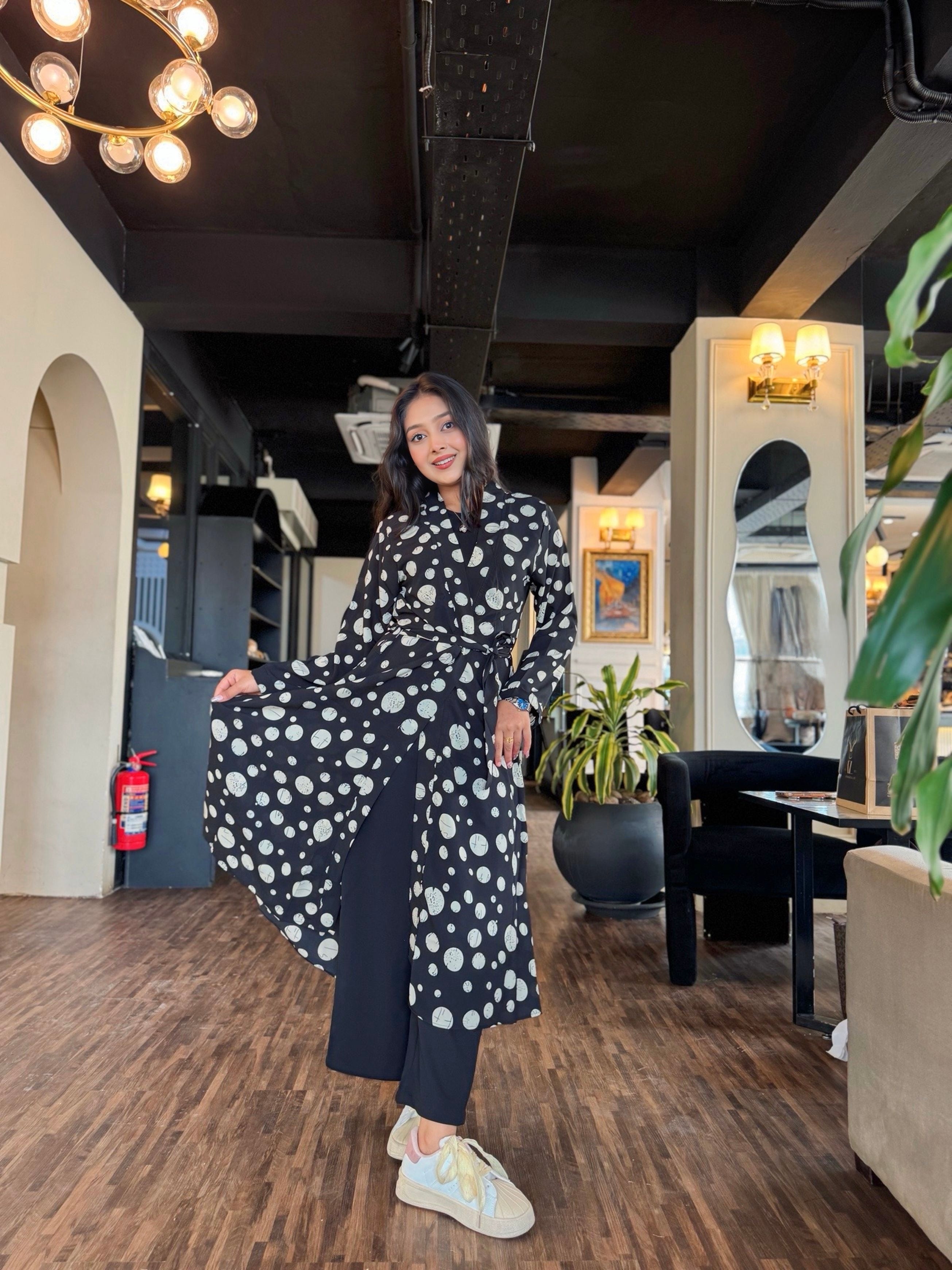 Woman in a polka dot dress posing in an indoor setting with modern decor.